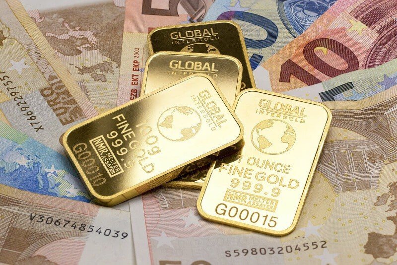 gold bullion bars laying on top of euro cash notes