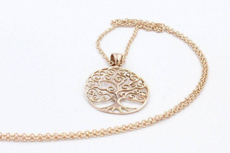 a gold tree of life pendant and chain on a white background