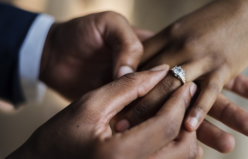 close up of a grrom putting a ring on his fiance's finger