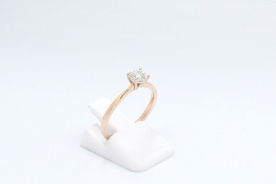 a rose gold solitaire diamond engagement ring on a white background