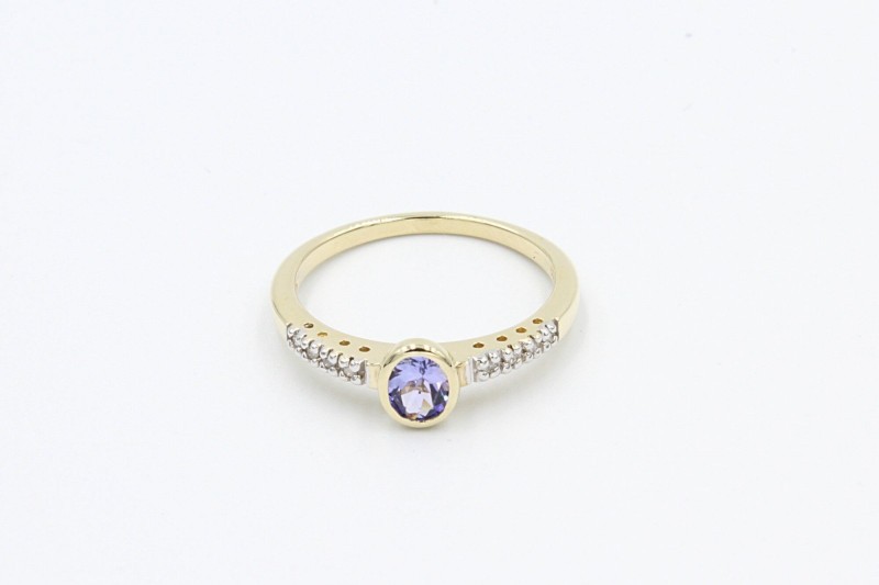 a tanzanite and gold engagement ring on a white background