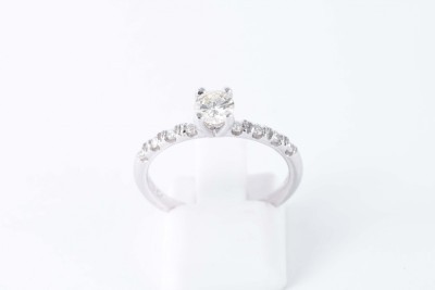 a white gold solitaire diamond engagement ring with diamond set shoulders on a white background