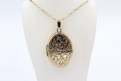 an gold pattern engraved cremation locket and chain on a white bust