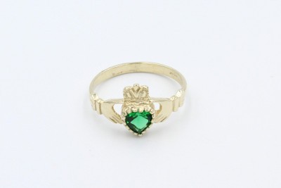 a gold claddag ring with a green heart shaped emerald on a white background