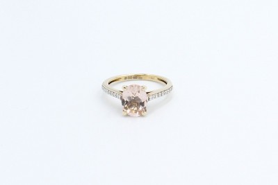 a solitaire oval shaped morganite engagement ring on a whit ebackground