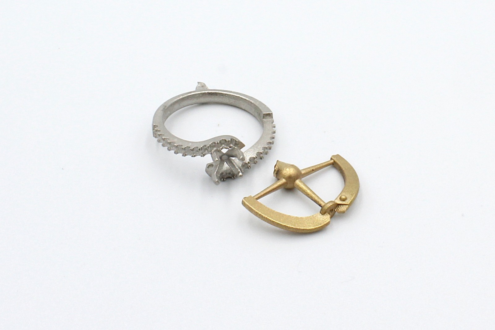 two parts of a raw and unpolished engagement ring on a white background