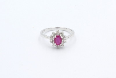 an oval ruby gem ring surround by a cluster of diamonds on a white background