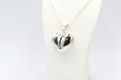 a silver heart-shaped ashes locket and chain on a white bust