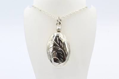 a silver engraved ashes locket and chain hanging from a white bust