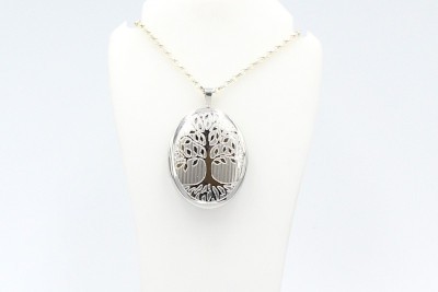 a silver cremation locket engraved with the tree of life on a white bust