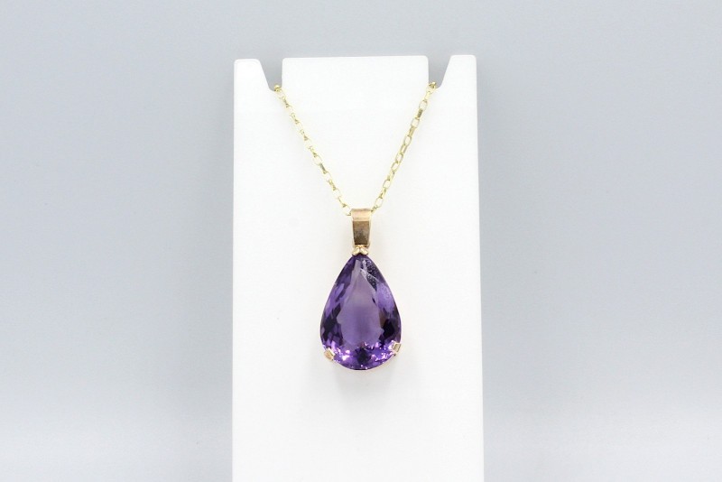 a large purple amethyst tear drop pendant on a gold chain