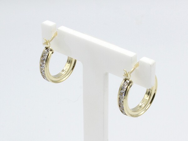 side view of gold cz hoop earrings on white stand