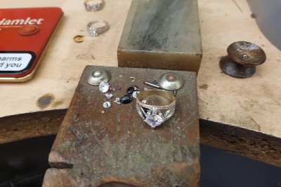 a diamond engagement ring and jewels laying on a jewellery workbench