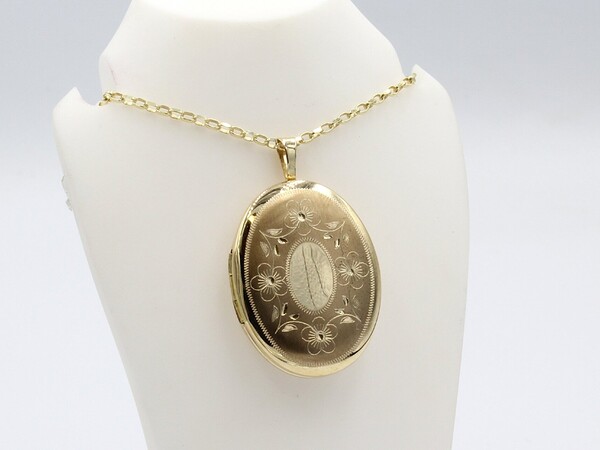 a gold engraved oval locket on a gold chain