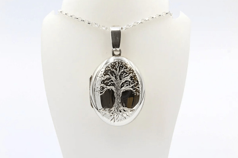 a silver pendant and chain engraved with the tree of life