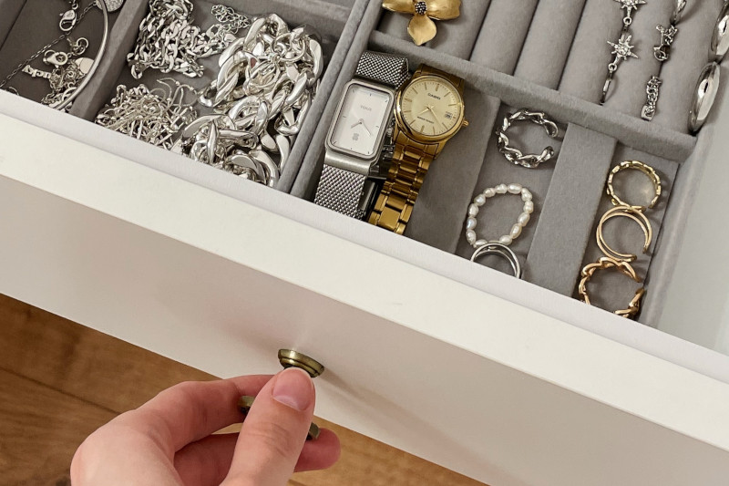 a person opening a white and grey drawer of a jewellery box
