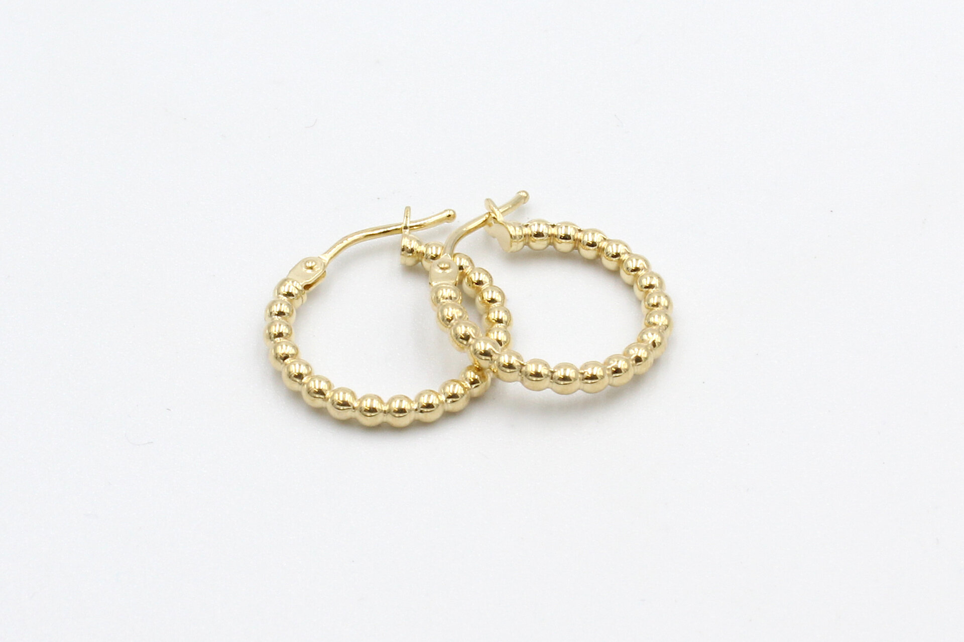a loose set of gold hoop earrings on a white background