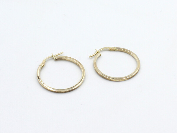 a set of gold hoop earrings handing from a white stand