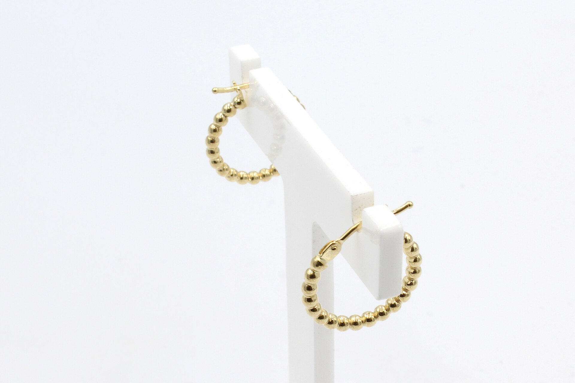 a set of gold hoop earrings on a white stand