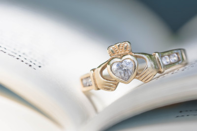 a gold claddagh ring on an open book