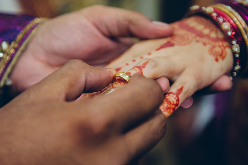 close up an indian couple putting on a wedding ring