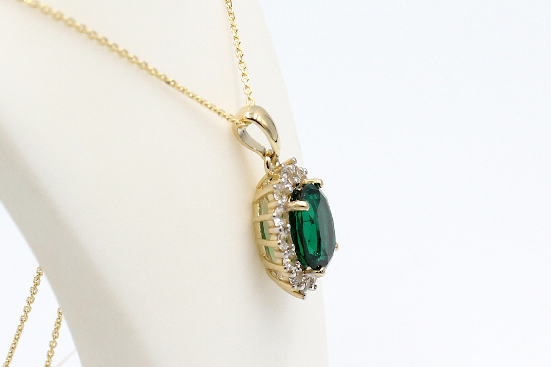 side view of a faux emerald halo pendant on a chain