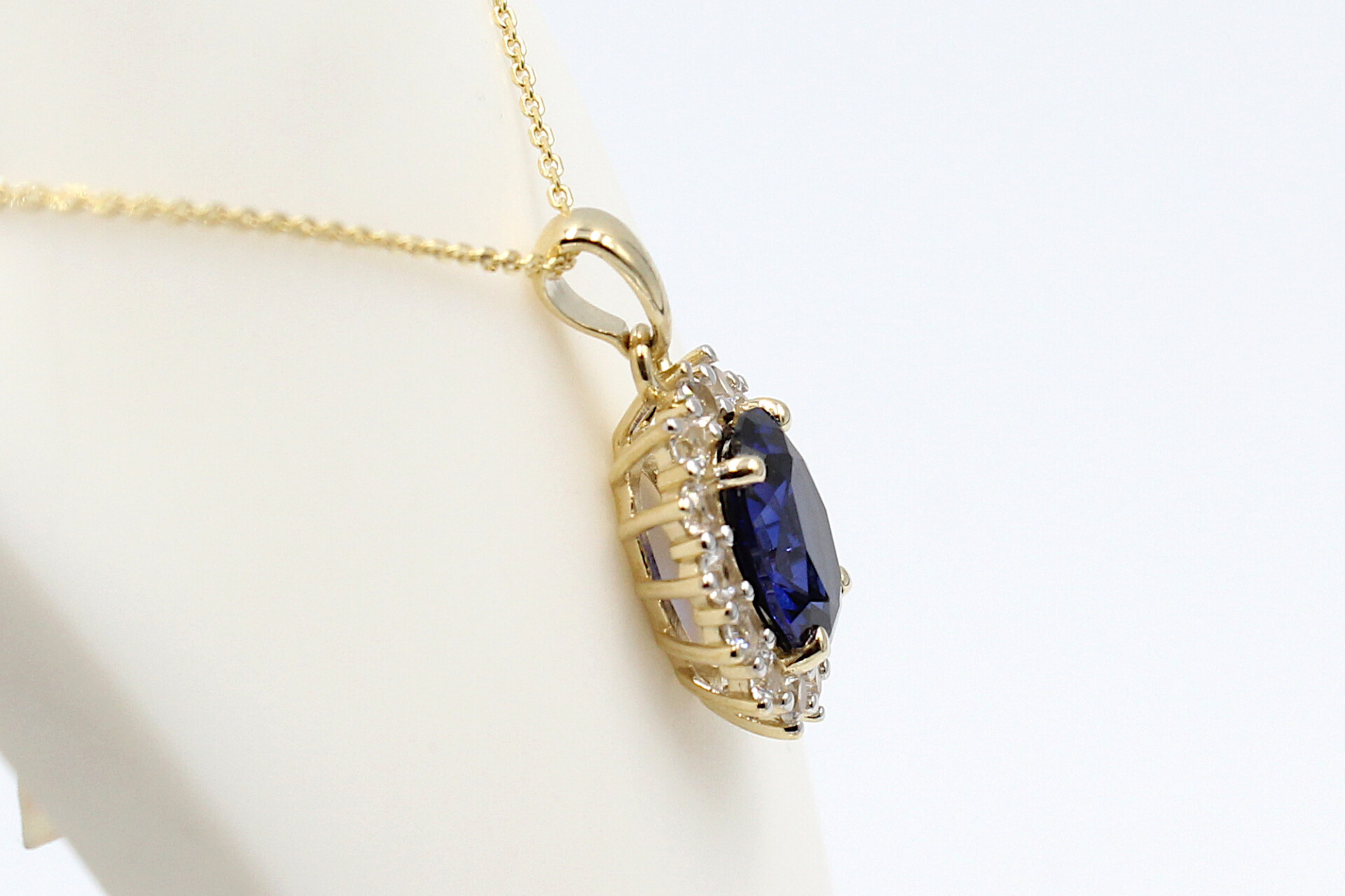 side view of a faux sapphire halo pendant on a chain