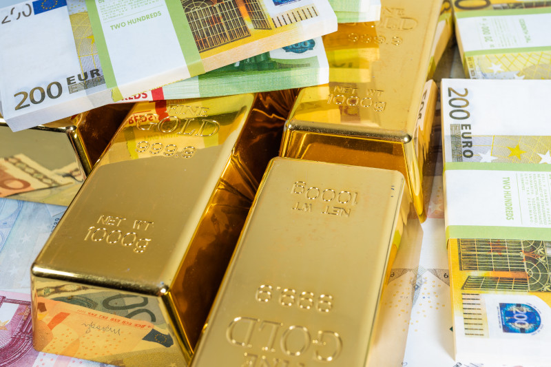 gold bullion bars next to money euro bank notes