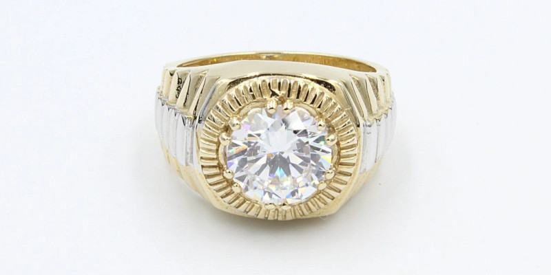 An engraved gold graduation ring with a large cubic zirconia gemstone