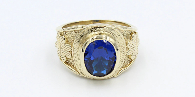 an engraved gold college ring with a large blue sapphire