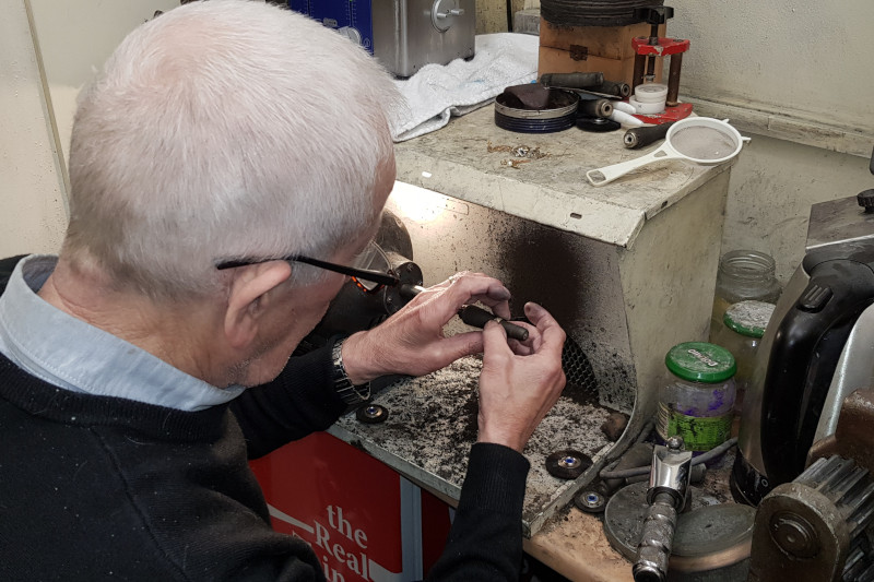 grey haired jeweller making a wedding ring