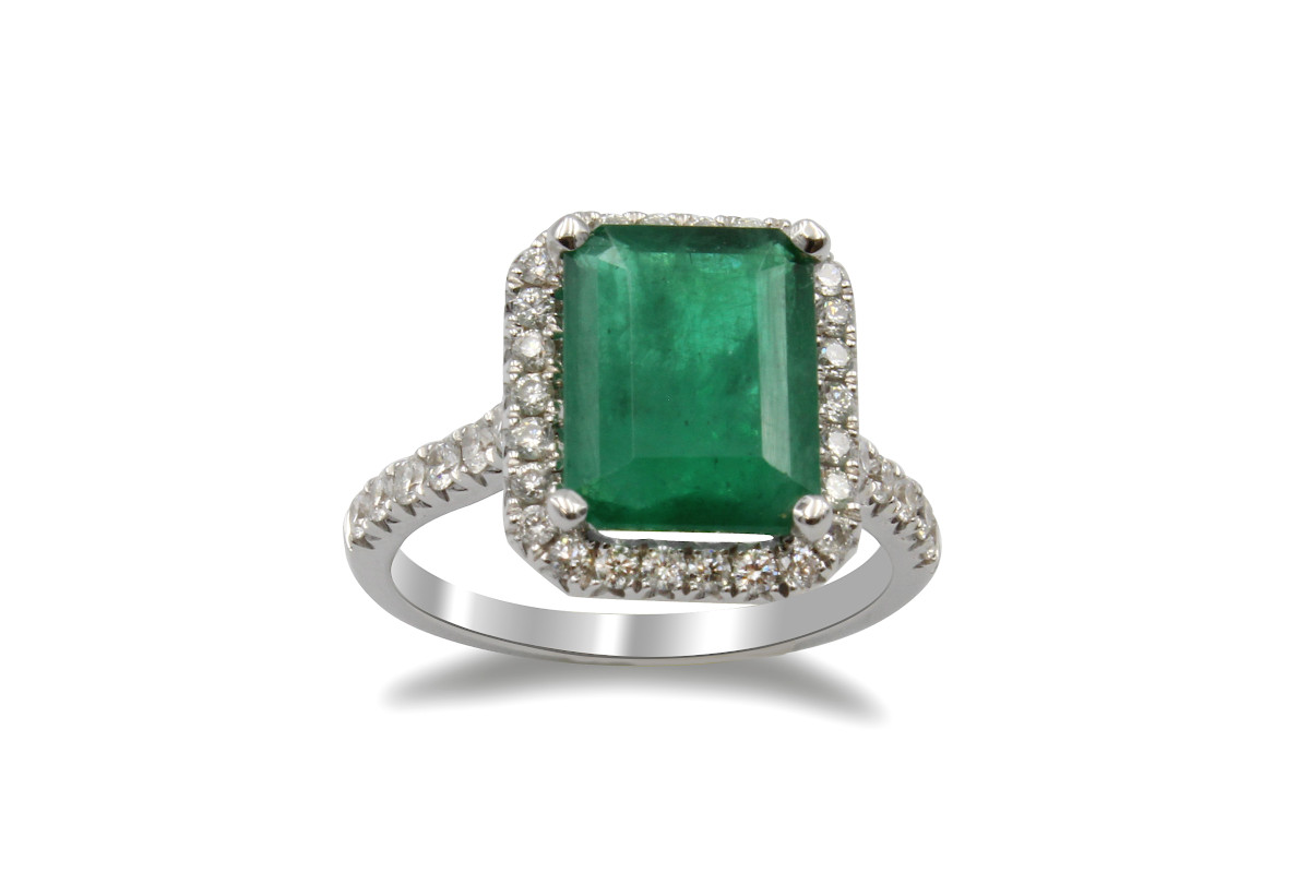 a halo engagement ring with one large emerald and a diamond halo