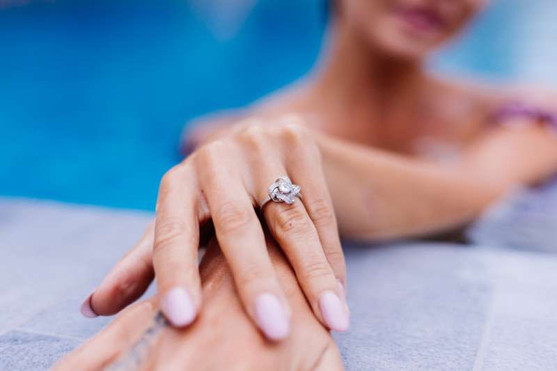 close up womans hands with manicured nails and diamond engagement ring